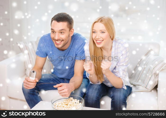 love, family, technology, entertainment and people concept - smiling couple watching tv and lying on sofa at home