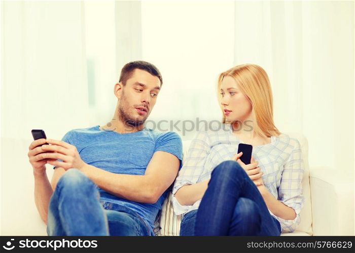 love, family, technology, internet and happiness concept - concentrated couple with smartphones at home