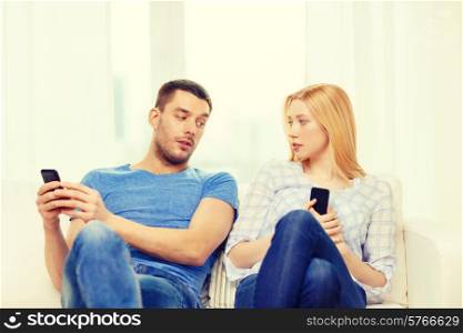 love, family, technology, internet and happiness concept - concentrated couple with smartphones at home