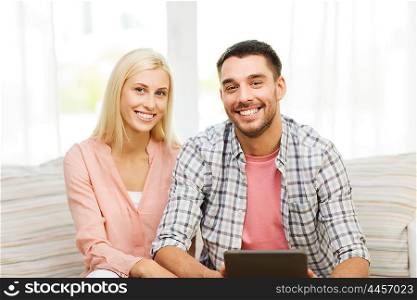love, family, technology, internet and happiness concept - smiling happy couple with tablet pc computer at home