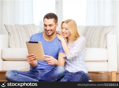 love, family, technology, internet and happiness concept - smiling happy couple witl tablet pc computer sitting on the floor at home