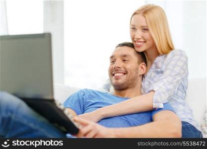 love, family, technology, internet and happiness concept - smiling happy couple witl laptop computer at home