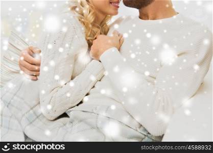 love, family, winter and happiness concept - close up of happy couple cuddling under paid at home
