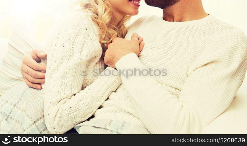 love, family, winter and happiness concept - close up of happy couple cuddling under paid at home. close up of happy couple cuddling at home