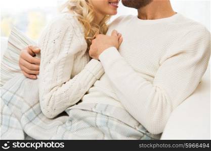 love, family, winter and happiness concept - close up of happy couple cuddling under paid at home