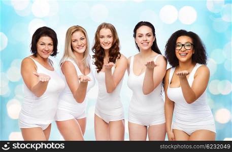 love, friendship, beauty, body positive and people concept - group of happy plus size women in white underwear sending blow kiss over blue holidays lights background
