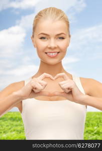 love, happiness and people concept - smiling woman showing heart shape gesture