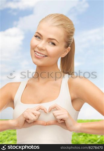 love, happiness and people concept - smiling woman showing heart shape gesture