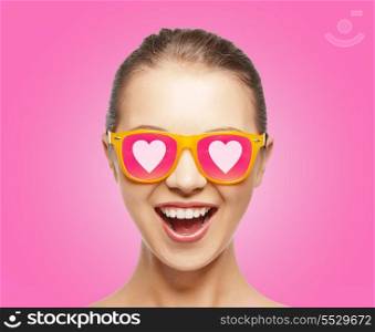 love, happiness and valentines day concept - amazed teen girl in sunglasses with hearts on pink background
