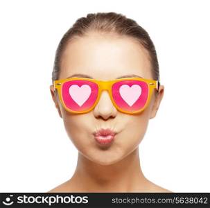 love, happiness, valentines day, face expressions and people concept - portrait of teenage girl in pink sunglasses with hearts blowing kiss