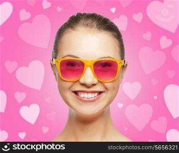 love, happiness, valentines day, face expressions and people concept - portrait of smiling teenage girl in pink sunglasses over background with hearts