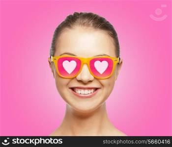 love, happiness, valentines day, face expressions and people concept - portrait of smiling teenage girl in pink sunglasses with hearts