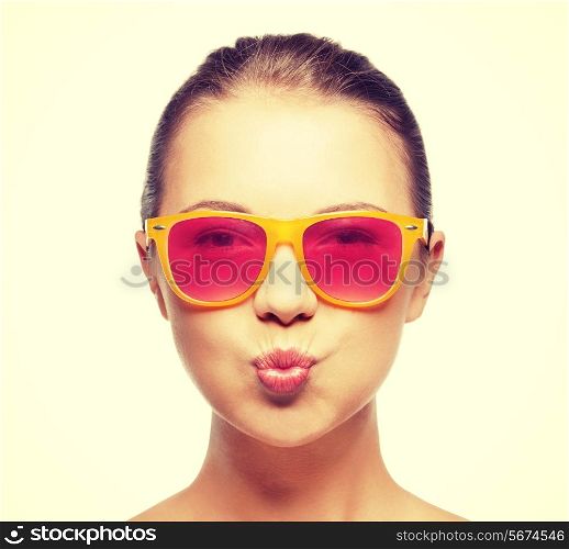 love, happiness, valentines day, face expressions and people concept - portrait of teenage girl in pink sunglasses blowing kiss