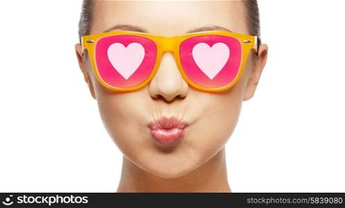 love, happiness, valentines day, face expressions and people concept - portrait of teenage girl in pink sunglasses with hearts blowing kiss