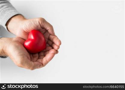 love, health, cardiology and charity concept - cupped senior man hands with red heart shape over white background. cupped senior man hands with red heart shape