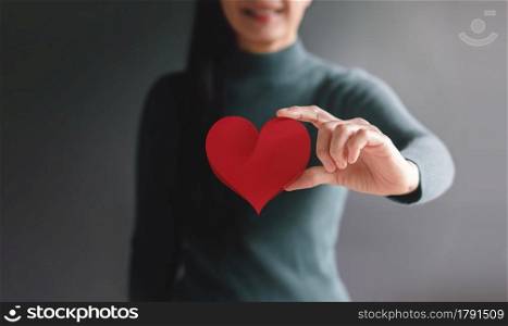 Love, Health Care, Donation and Charity Concept. Close up of Smiling Volunteer Woman Holding a Heart Shape Paper. presenting to Camera