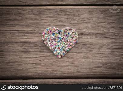 Love heart shape from colorful glitter place in the middle of wood background with vignette, anniversary and valentine&rsquo;s day symbol