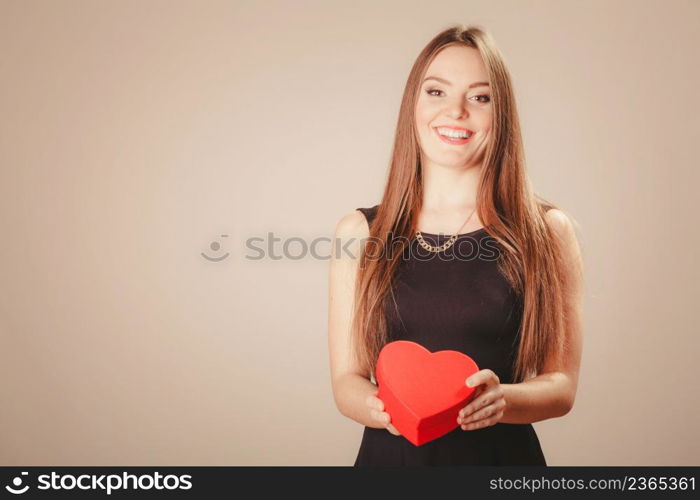 Love help and charity concept. Young beauty happy long haired woman girl in black dress holding heart box gift in studio.. Happy girl with heart