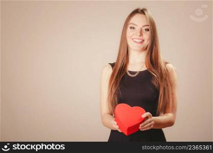 Love help and charity concept. Young beauty happy long haired woman girl in black dress holding heart box gift in studio.. Happy girl with heart