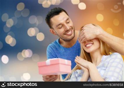 love, holiday, celebration and family concept - happy couple with present over lights background. happy couple with present over lights background