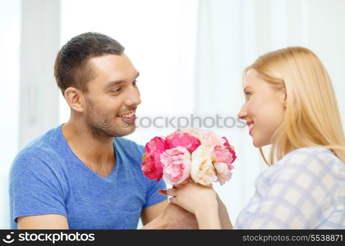 love, holiday, celebration and family concept - smiling man giving girfriens flowers at home