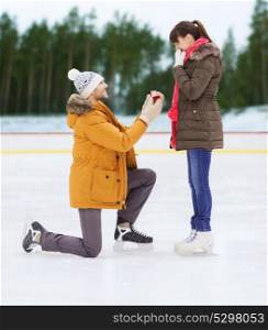 love, holidays and relationships concept - happy couple with engagement ring at outdoor skating rink. happy couple with engagement ring on skating rink