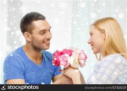 love, holidays, celebration, people and family concept - smiling man giving girlfriend flowers at home