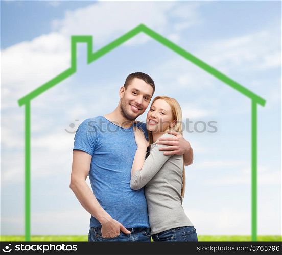 love, home, people and family concept - smiling couple hugging over green house and blue sky with grass background