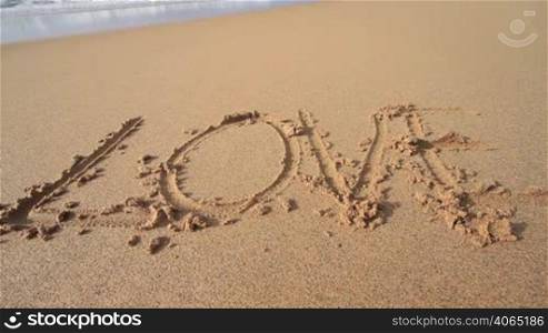 ""Love" in den Sand am Strand geschrieben"