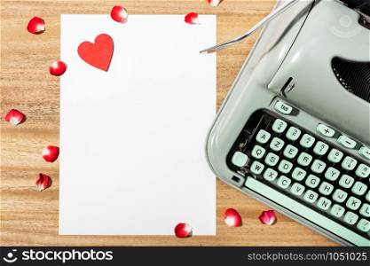 Love letter. Desk with blank paper, retro typewriter and red heart. Love concept