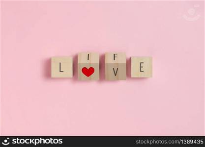 LOVE, LIFE text and red heart on Wooden cubes on pink background. Valentine?s day concepts.