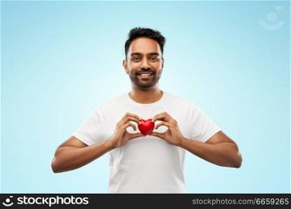 love, medicine, charity and healthcare concept - smiling indian man with red heart over blue background. indian man with red heart over blue background