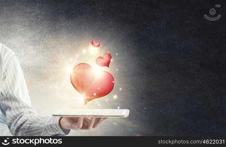 Love online. Male hand holding tablet pc with red heart on screen