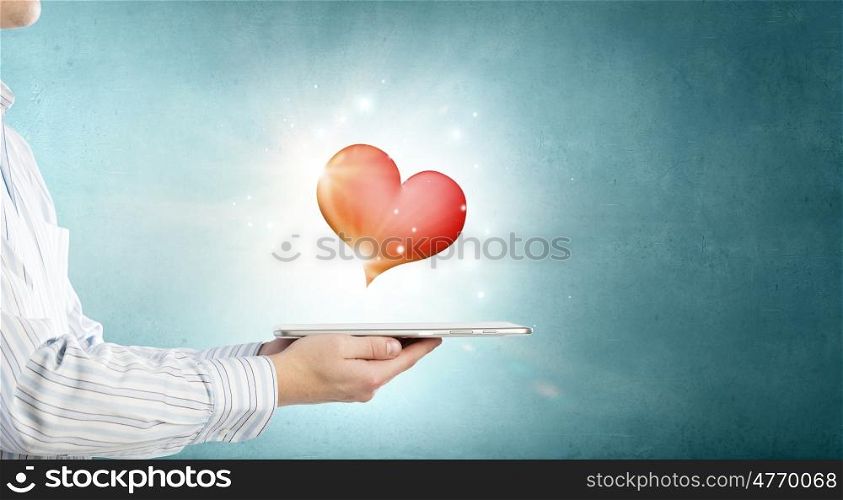 Love online. Male hand holding tablet pc with red heart on screen