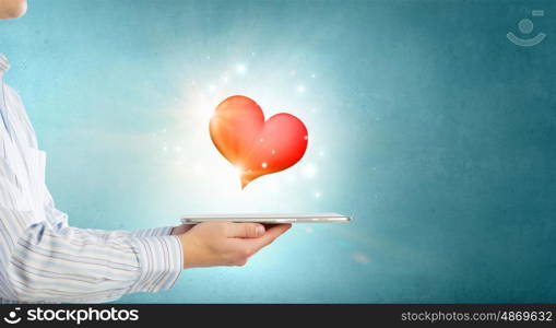Love online. Male hand holding tablet pc with red heart on screen