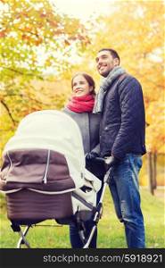 love, parenthood, family, season and people concept - smiling couple with baby pram in autumn park