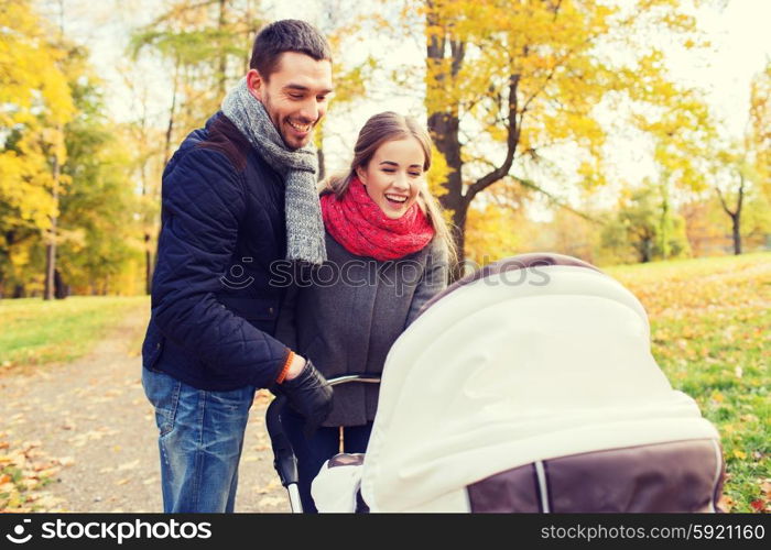 love, parenthood, family, season and people concept - smiling couple with baby pram in autumn park