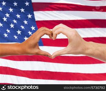 love, patriotism, gesture, peace and people concept - closeup of two hands showing heart shape over american flag