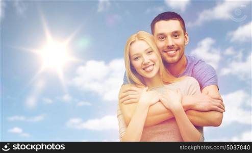 love, people and family concept - happy smiling couple hugging over sky and sun background. happy smiling couple hugging over sky and sun