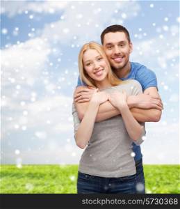 love, people and family concept - smiling couple hugging over blue sky, snow and grass background