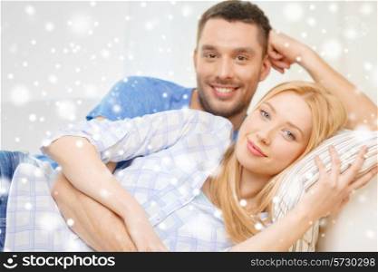 love, people and family concept - smiling couple lying on sofa and hugging at home