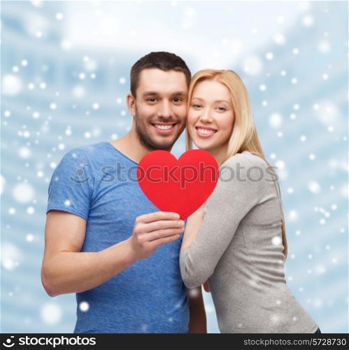 love, people and family concept - smiling couple with red paper heart shape hugging over snow and city buildings background