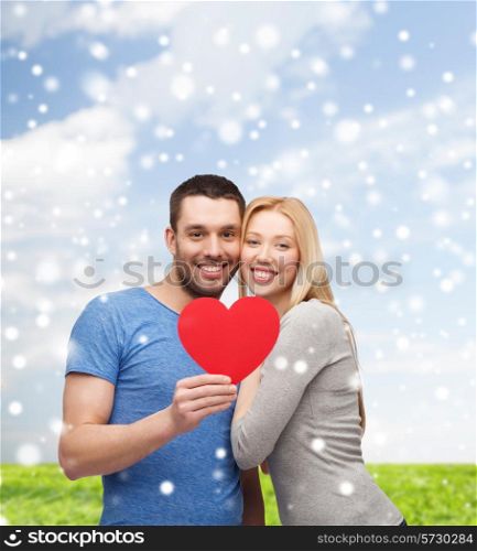 love, people and family concept - smiling couple with red paper heart shape hugging over blue sky, snow and grass background