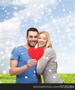 love, people and family concept - smiling couple with red paper heart shape hugging over blue sky, snow and grass background
