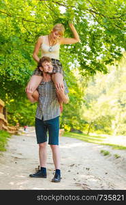 Love people and happiness concept. Travel loving couple having fun outdoor in forest. Man carrying his beautiful girlfriend on shoulders while walking