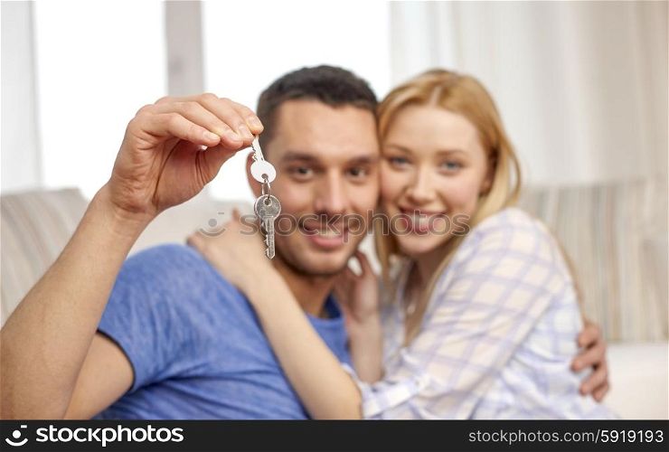 love, people, real estate, home and family concept - smiling couple showing keys over living room background