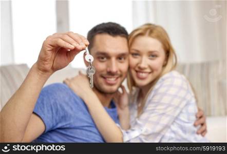 love, people, real estate, home and family concept - smiling couple showing keys over living room background