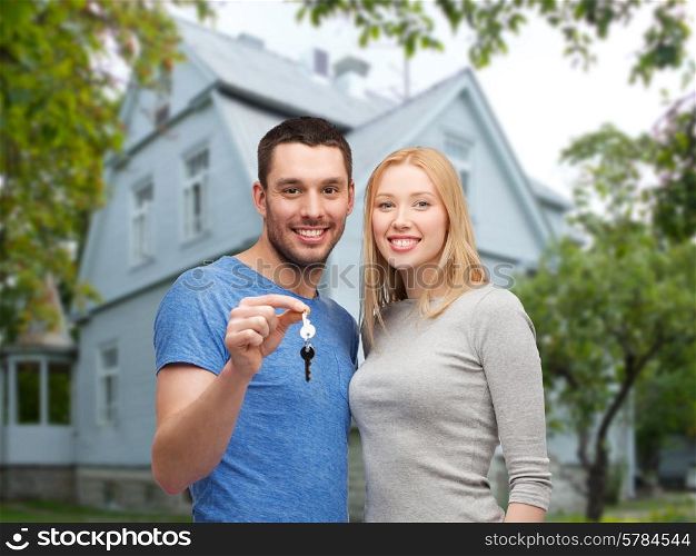 love, people, real estate, home and family concept - smiling couple showing key over house background