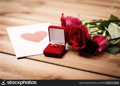 love, proposal, valentines day and holidays concept - close up of gift box with diamond engagement ring, red roses and greeting card on wood (vintage effect)