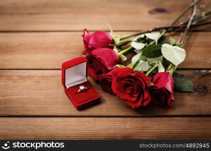 love, proposal, valentines day and holidays concept - close up of gift box with diamond engagement ring and red roses on wood (vintage effect)